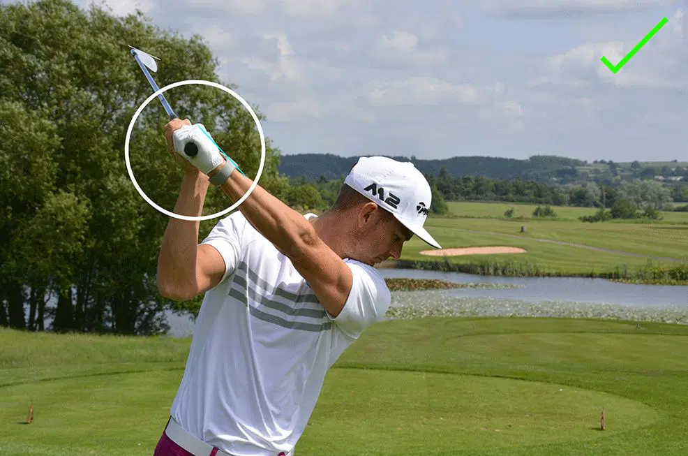 \"Golfer Golfer completing backswing, wrist position highlighted, checkmark indicates correct form.